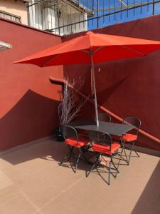een tafel en stoelen met een rode parasol bij La Petit Maison Elena in Sanremo
