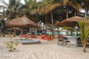 plaża ze stołami, krzesłami i parasolami na plaży w obiekcie Rainbow beach resort w mieście Sanyang