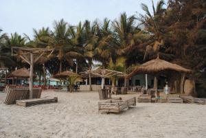 uma praia com cadeiras e guarda-sóis e palmeiras em Rainbow beach resort em Sanyang