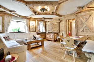 uma sala de estar com um sofá branco e tectos em madeira em Brand new beautiful 3 bedroom few steps from centre em Cortina dʼAmpezzo