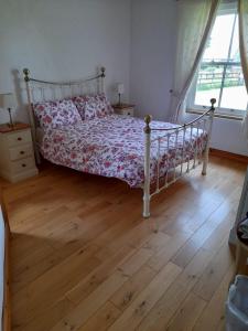 a bedroom with a bed and a wooden floor at Katy Kellys Countryside Self Catering Cottage in Roscommon