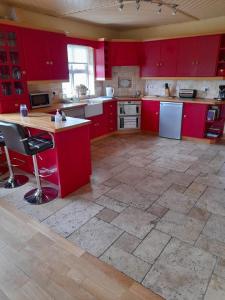 uma grande cozinha com armários vermelhos e piso em azulejo em Katy Kellys Countryside Self Catering Cottage em Roscommon