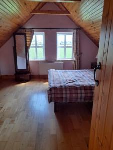 Katy Kellys Countryside Self Catering Cottage في روسكومون: غرفة نوم مع سرير في غرفة مع نوافذ