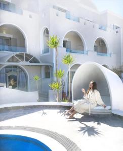 a woman sitting on a chair next to a swimming pool at Blue Suites in Fira