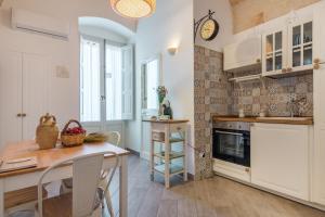 eine Küche mit einem Tisch und einer Uhr an der Wand in der Unterkunft CIVETTHOUSE : la casa delle civette in Polignano a Mare