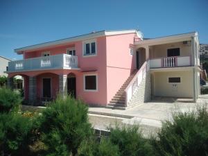 a pink house with stairs and a balcony at Apartmani Peko in Pag
