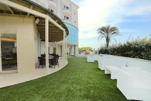 budynek z białymi ławkami na zielonym trawniku w obiekcie Blue Paradise Hotel w San Mauro a Mare