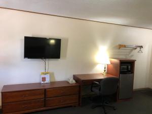 a hotel room with a desk and a television on the wall at Budget Host Inn - Emporia in Emporia