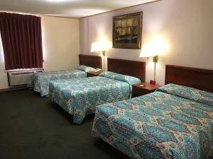 a hotel room with three beds and two lamps at Budget Host Inn - Emporia in Emporia