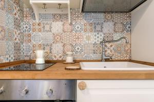 una cucina con lavandino e parete piastrellata di CIVETTHOUSE : la casa delle civette a Polignano a Mare
