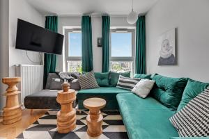 a living room with a green couch and a tv at Queen's Gambit by Blue Mandarin in Gdańsk