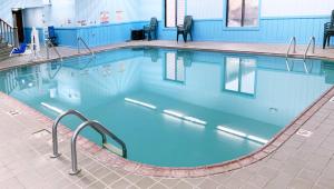 een groot zwembad met blauw water bij Magnuson Hotel Country Inn in Ishpeming