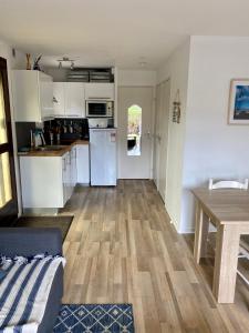 a kitchen with white cabinets and a wooden floor at Rez de jardin CABOURG in Cabourg