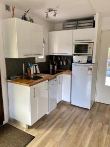 a kitchen with white cabinets and a white refrigerator at Rez de jardin CABOURG in Cabourg