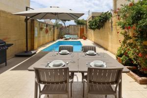 a table with chairs and an umbrella next to a pool at Superb Maltese Farmhouse with Private Pool in Victoria