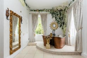 uma casa de banho com uma banheira e um espelho grande em RainHill Hall Hotel em Rainhull