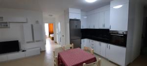 a kitchen with white cabinets and a red table and chairs at Apartment Suite Family in Shëngjin
