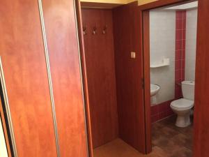 a bathroom with a toilet and a wooden door at Pensjonat Anker pokoje in Ustronie Morskie +80 photos