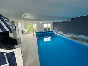 a swimming pool in a house with a blue ceiling at Ferienwohnung im Poolhaus mit Ostseeblick in Wittenbeck