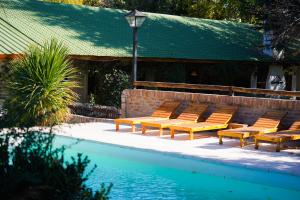 a group of chairs sitting next to a swimming pool at Casa de Coria in Chacras de Coria