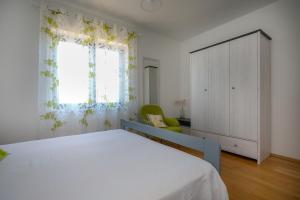 een slaapkamer met een bed, een kast en een raam bij Apartments Jagoda in Vrbnik