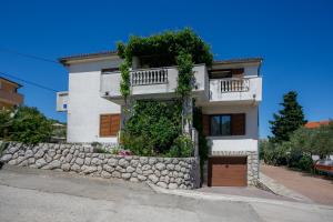 een wit huis met een stenen steunmuur bij Apartments Jagoda in Vrbnik