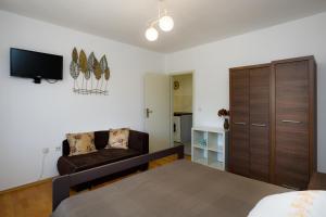 een slaapkamer met een bed, een bank en een tv bij Apartments Jagoda in Vrbnik