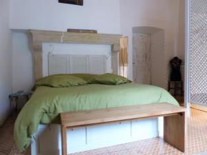 un lit avec une tête de lit en bois et un banc en bois dans l'établissement Plume Et Pinceau, à Montdragon