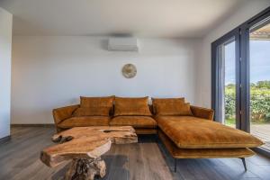uma sala de estar com um sofá castanho e uma mesa de madeira em Résidence Pierre & Vacances Premium Les Terrasses d'Arsella em Porto-Vecchio