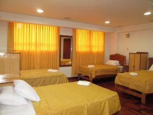 una camera d'albergo con tre letti con lenzuola gialle di Hotel Panamericano a Lima