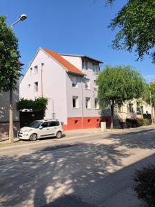 un coche blanco estacionado frente a un edificio en Alpesi Apartman en Sopron