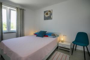 a bedroom with a white bed and a blue chair at Oliva in Vrbnik