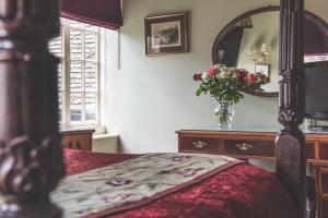 a bedroom with a bed and a vase of flowers at Jeakes House in Rye