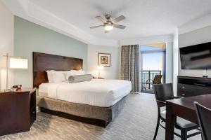 a hotel room with a bed and a desk and a table at Anderson Ocean Club and Spa by Oceana Resorts in Myrtle Beach