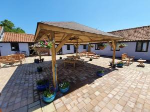 a wooden pavilion with a picnic table and benches at Low Farm Cottages in Woodbridge