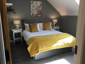 a bedroom with a bed with a yellow blanket and two tables at Knockaguilla House Bed & Breakfast in Doolin