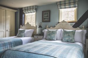 two beds in a bedroom with blue walls and windows at Jeakes House in Rye