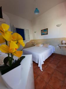 een slaapkamer met een bed met gele bloemen op de voorgrond bij Turismo Egadi - Appartamenti in Favignana