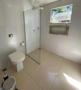 Un baño blanco con inodoro y ventana. en Suite Confortavel em Chapada dos Guimaraes, en Chapada dos Guimarães