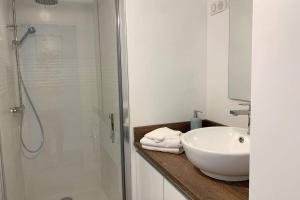 a white bathroom with a sink and a shower at Le Charmant, appartement situé dans la résidence de standing, les Dunes du Golf à Wimereux in Wimereux