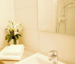 W łazience znajduje się umywalka, lustro i waza kwiatów. w obiekcie KELKO 1A Hotel w mieście Kehl