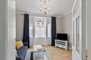 Bay Apartment في هيلينسبورغ: غرفة معيشة مع أريكة زرقاء وتلفزيون