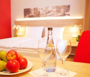 a table with two wine glasses and a plate of fruit at KELKO 1A Hotel in Kehl am Rhein