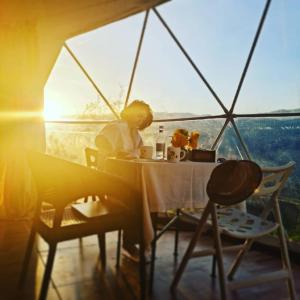a person sitting at a table in a room with a view at Yenokavan Glamping in Ijevan