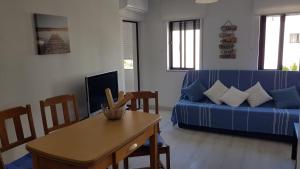a living room with a blue couch and a table at Apartment Girasol Front Beach Quarteira Algarve in Quarteira