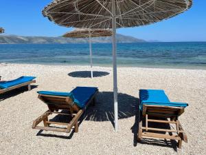 dwa krzesła i parasol na plaży w obiekcie Karaburun Sunset Beach w mieście Orikum