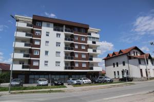 a large apartment building with cars parked in front of it at Apartman Lilly in Modriča
