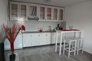 a kitchen with white cabinets and a table and stools at Apartman Lilly in Modriča