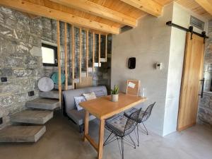 ein Esszimmer mit einem Tisch, Stühlen und einer Steinmauer in der Unterkunft Windmills Village Amarynthos in Amarinthos