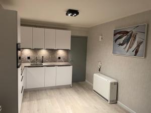 Una cocina con gabinetes blancos y un refrigerador. en Zeedijk Westende Nautilus, en Middelkerke 15 fotos más